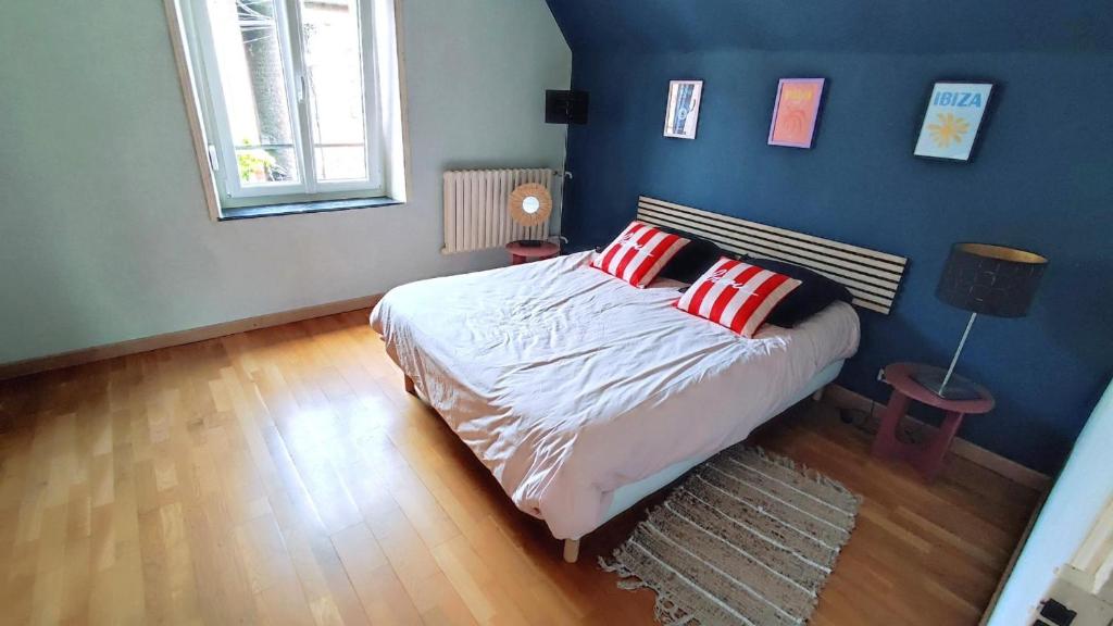 a bedroom with a bed with two red pillows at La maison du voyageur toque in Charleville-Mézières