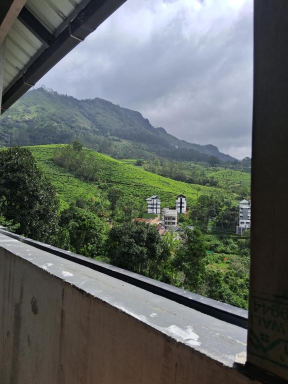 una ventana con vistas a una colina verde en Dream Casa, en Anachal