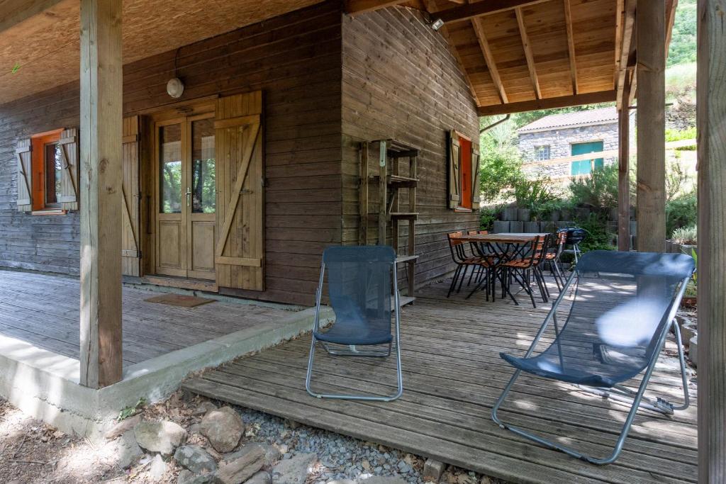 eine Veranda eines Hauses mit zwei Stühlen und einem Tisch in der Unterkunft Chalet Orange - Piscine Partagée in Darbres