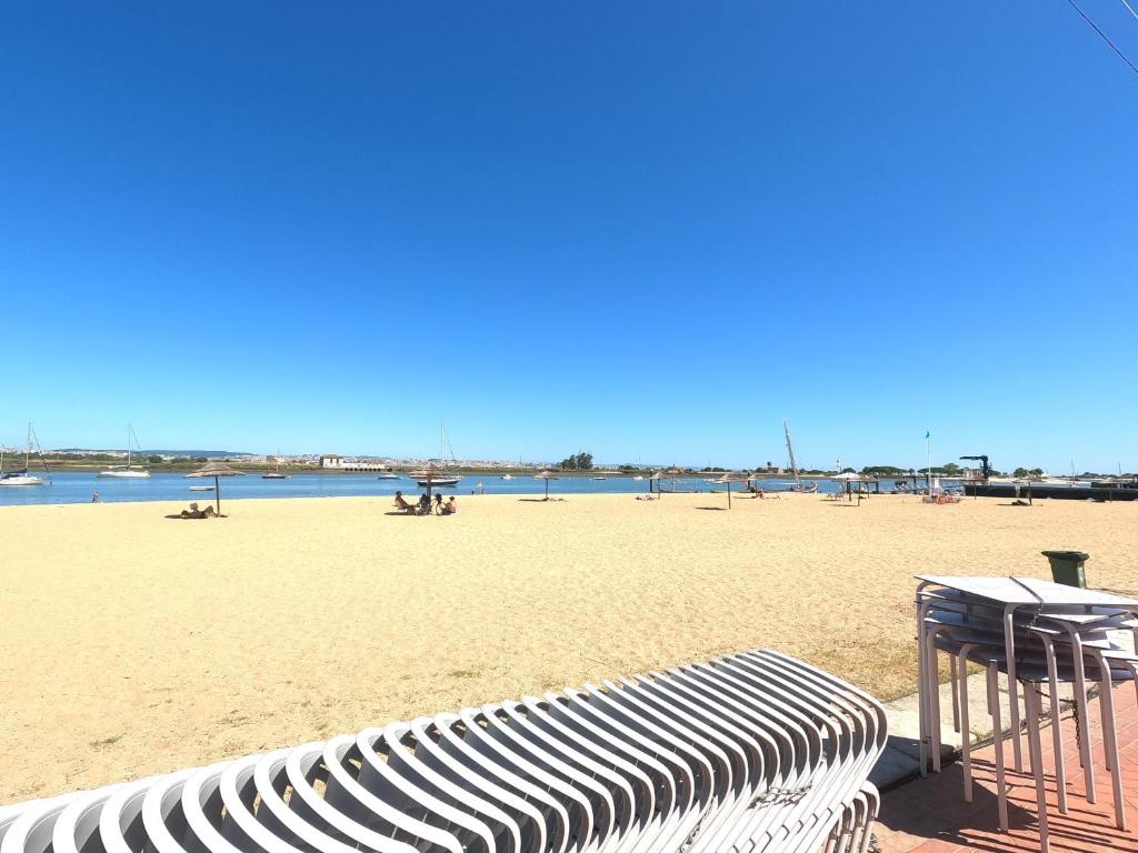 a bench on a beach with the ocean in the background at Almada, Seixal T0 in Seixal