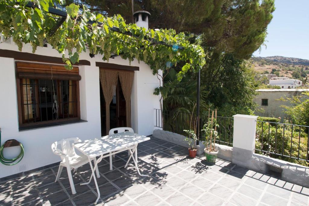 a patio with a table and chairs in front of a house at Casa Loles in Capileira