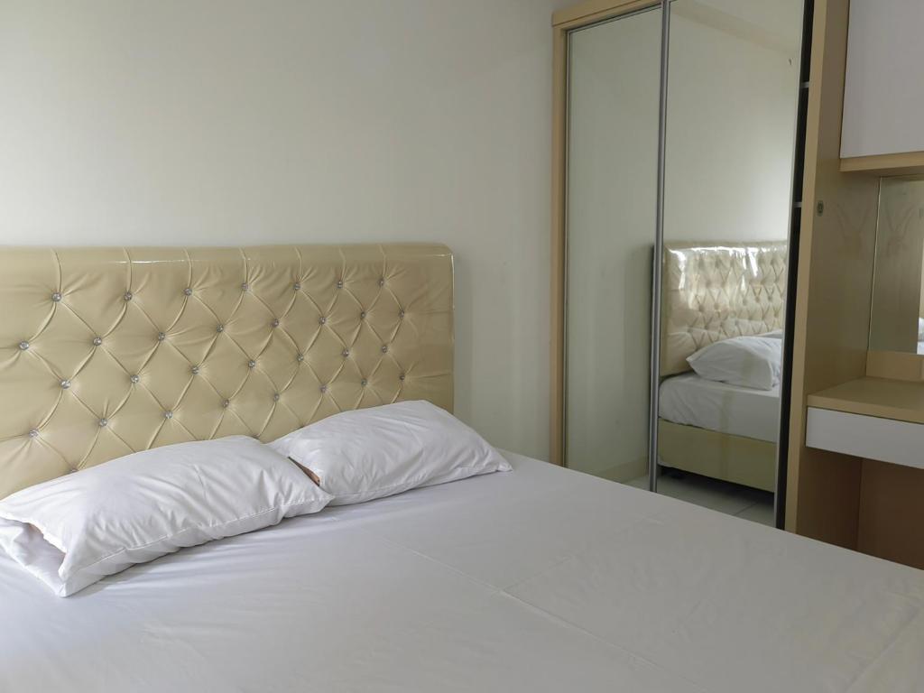 a bedroom with a white bed and a mirror at Podomoro Golf View By Arsakha Property Management in Tjikuda Tiga