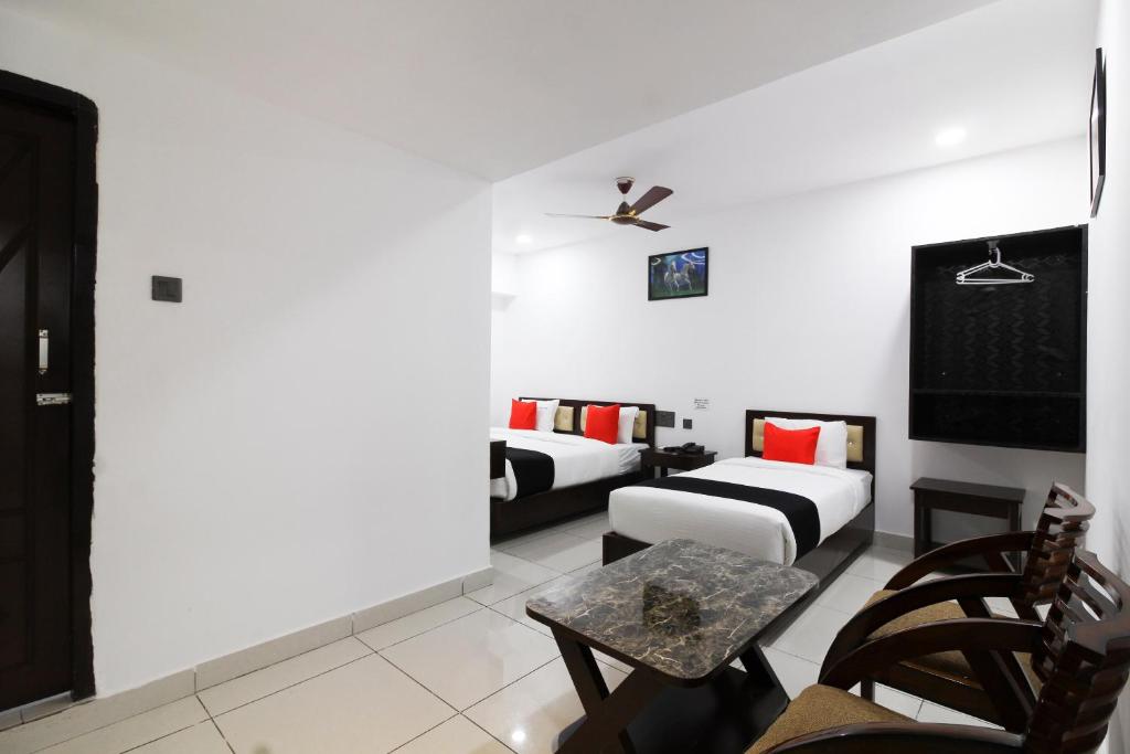 a living room with two beds and a table at Collection O Mythri Hotel Near By ECIL, AS RAO Nagar, Sainikpuri in Hyderabad