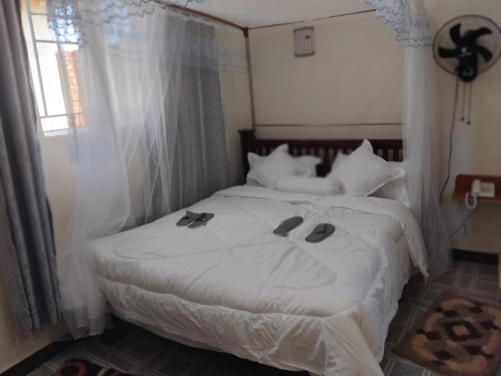 a bedroom with a white bed with slippers on it at Sea Ville Resort Hotel And Spa Limited in Mayuge