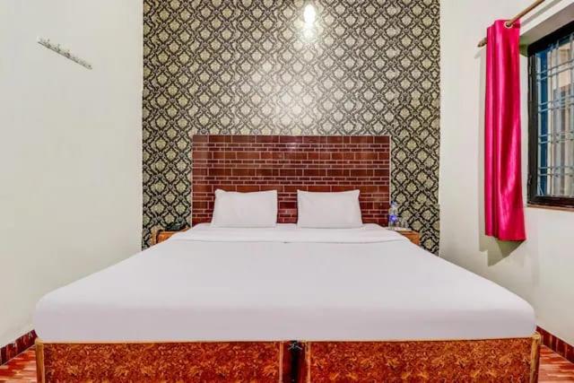 a large bed in a room with a red curtain at Butola guest house in Dehradun