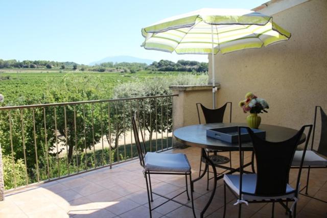 une terrasse avec une table, des chaises et un parasol dans l'établissement Vacances Vaison la Romaine, à Vaison-la-Romaine