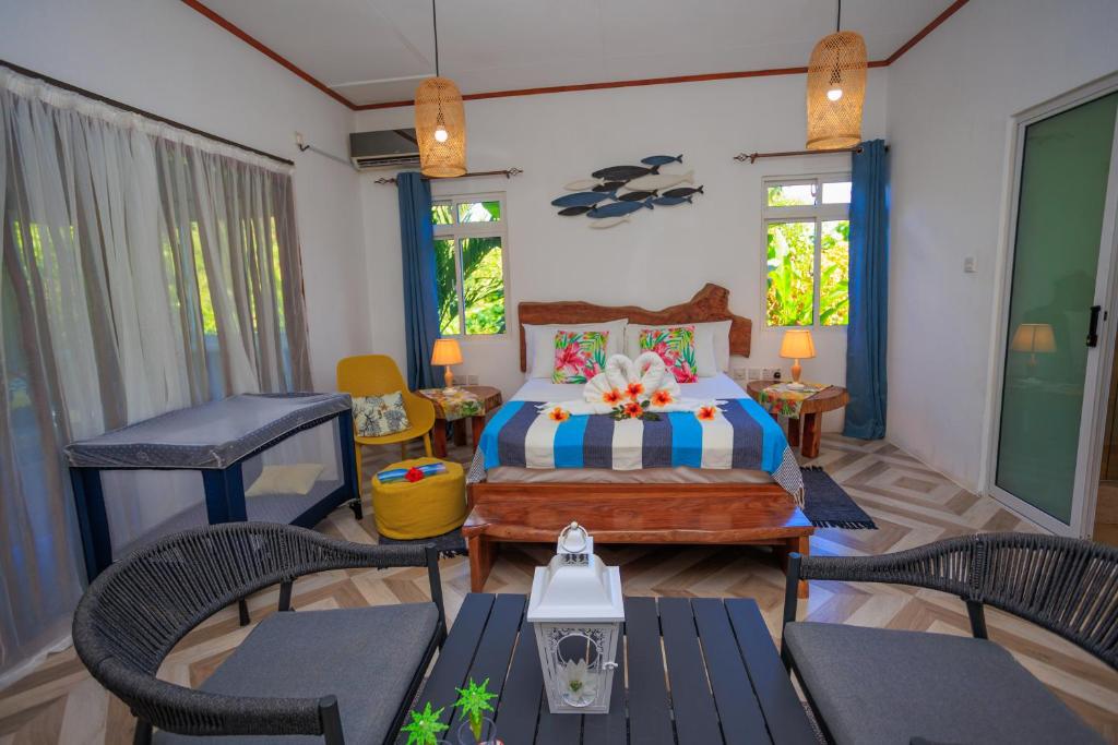 a bedroom with a bed with chairs and a table at Milles Montagnes Residence in Anse a La Mouche