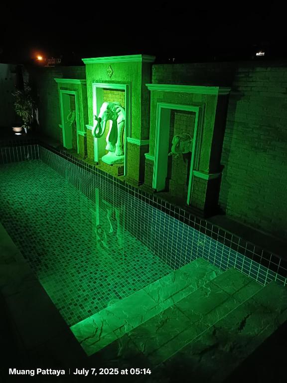 乔木提恩海滩Emerald hotel的夜晚建筑物内有雕像的游泳池