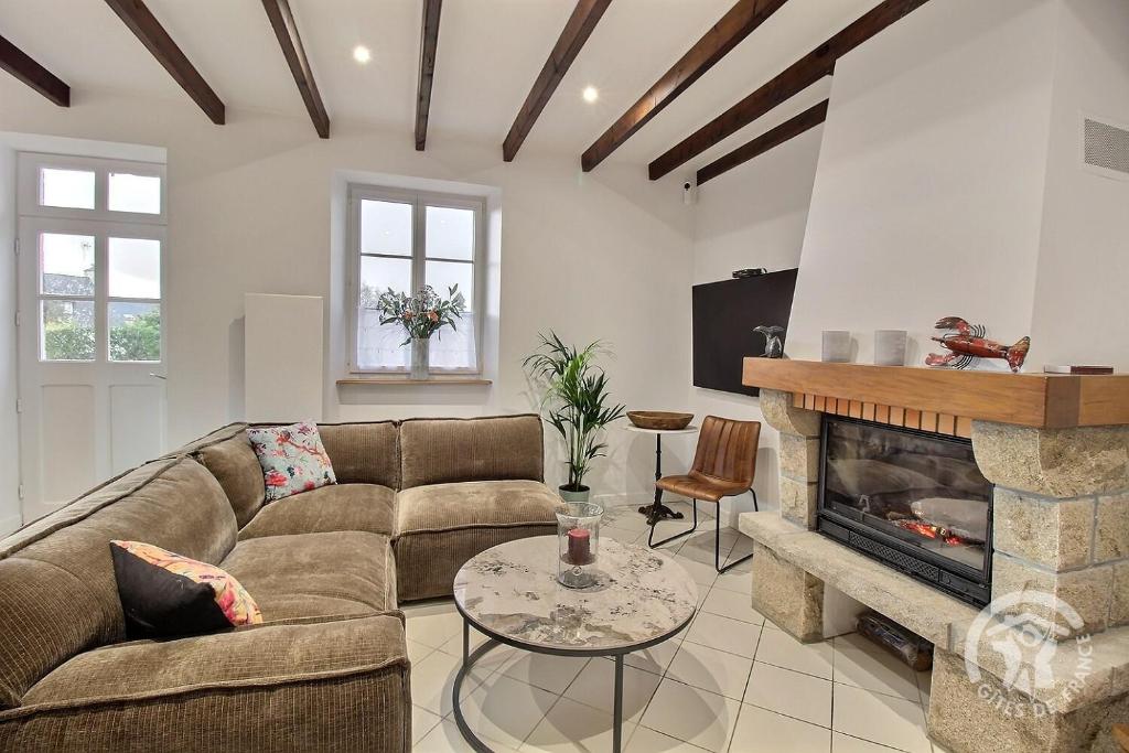 a living room with a couch and a fireplace at La maison de la plage à 6 in Trégastel