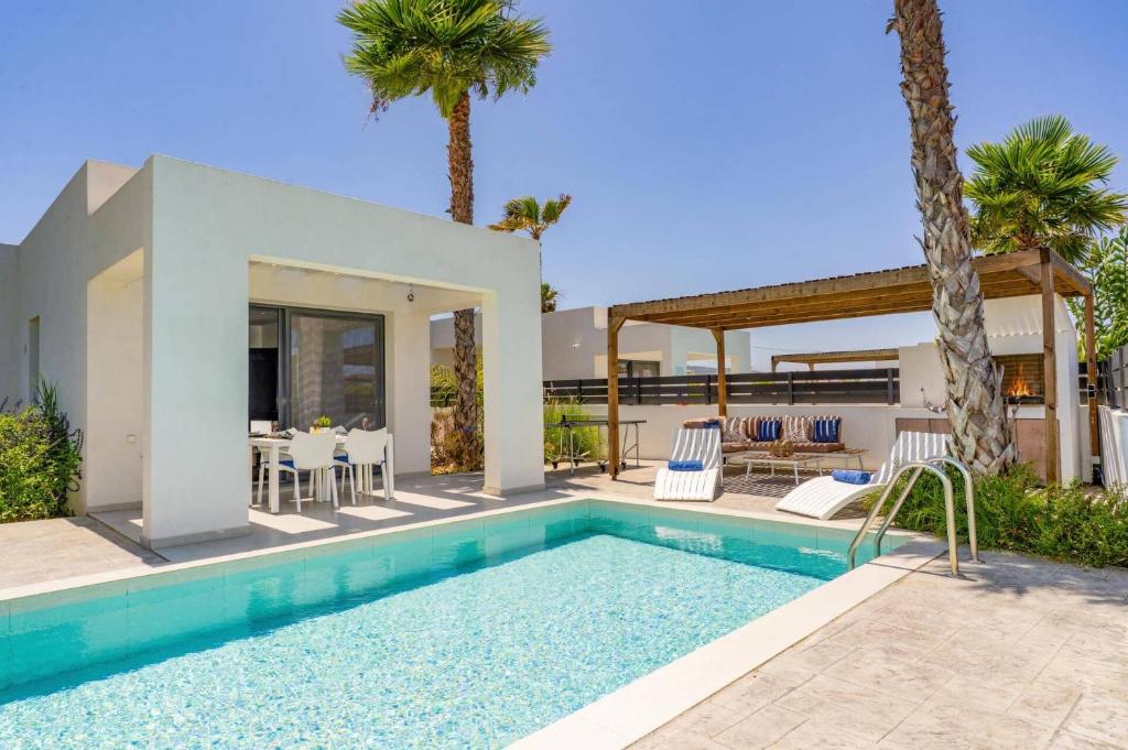 a villa with a swimming pool and a house at Villa Palm Vista by Villa Plus in Kremasti