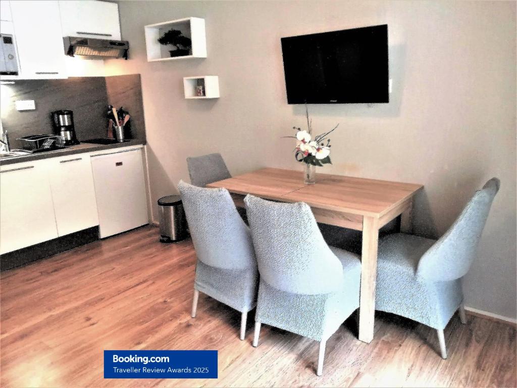 une table de salle à manger avec des chaises bleues et une télévision dans l'établissement Charmant T2, hypercentre, calme, terrasse, parking, à Luchon