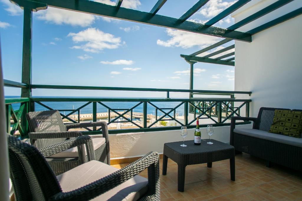 a balcony with chairs and a table with wine glasses at Lanzholidays in Tías