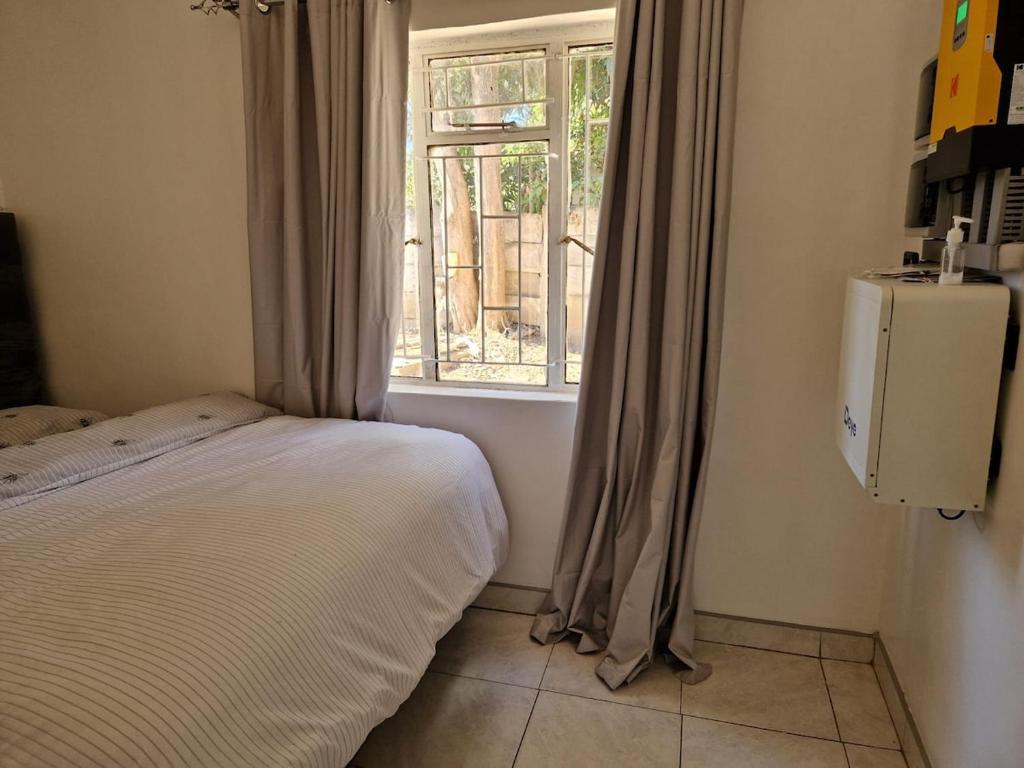 a bedroom with a bed and a window at Cosy Harare Haven Cottage in Harare