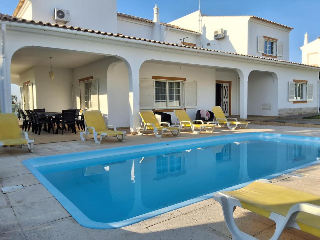 una piscina con sillas y una casa en Villa Relax, en Bicas