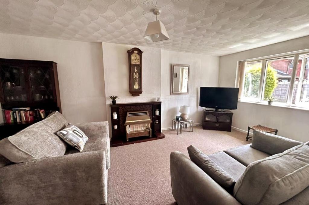 a living room with a couch and a tv at Oldham Bungalow Retreat: 2BD Peaceful Comfort in Lees