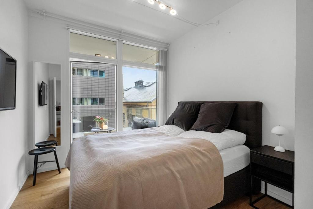 a white bedroom with a large bed and a window at Heart of Aarhus, modern apartment and paid parking nearby in Aarhus