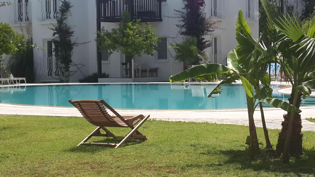 une chaise assise dans l'herbe à côté d'une piscine dans l'établissement Meis Hotel, à Bitez