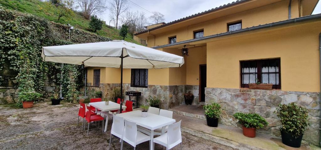 einen Tisch und Stühle mit einem Regenschirm vor einem Gebäude in der Unterkunft Río España - 5 habitaciones in San Miguel