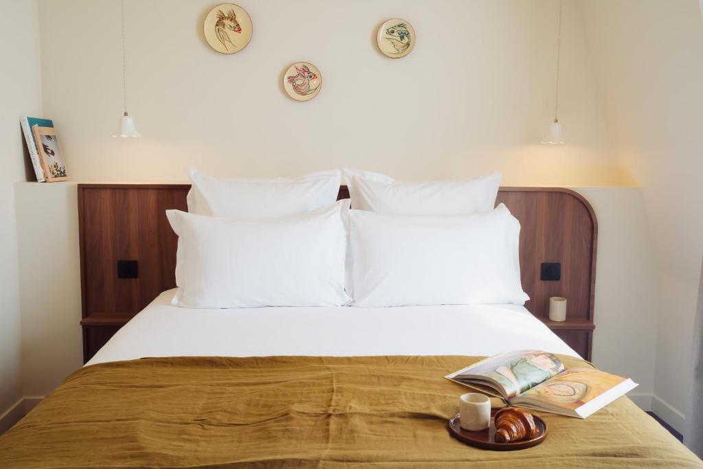 a bedroom with a bed with white pillows and a book at LALA Hôtel in Paris