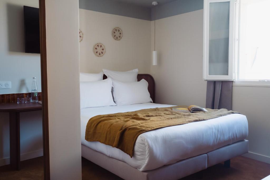 een slaapkamer met een bed, een tafel en een raam bij LALA Hôtel in Parijs