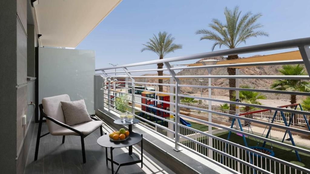 a balcony with a chair and a table and palm trees at Boutique apartment with spectacular view of the Eilat mountains in Eilat