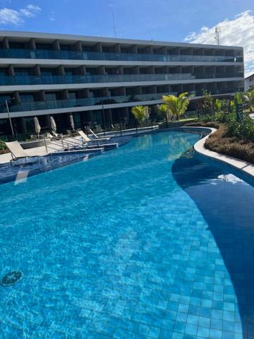 a large blue swimming pool in front of a building at FLAT BEACH CLASS SUMMEr PORTO DE GALINHAS in Porto De Galinhas