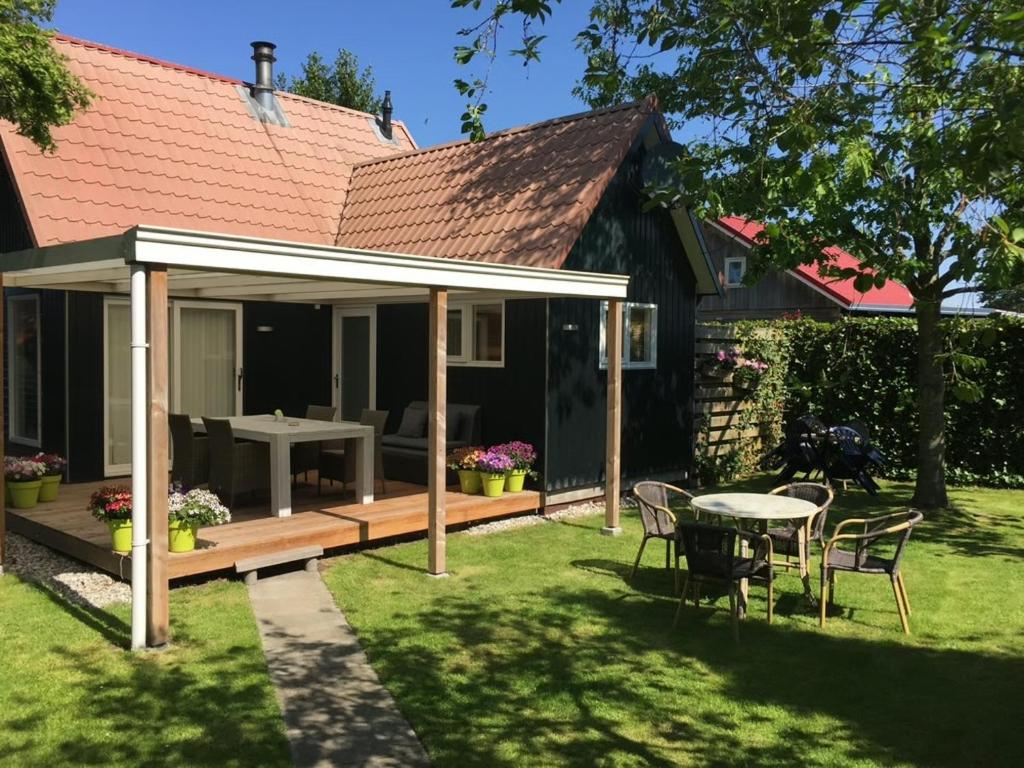 a house with a deck and a table and chairs at Huisje Meerweg in Rohel