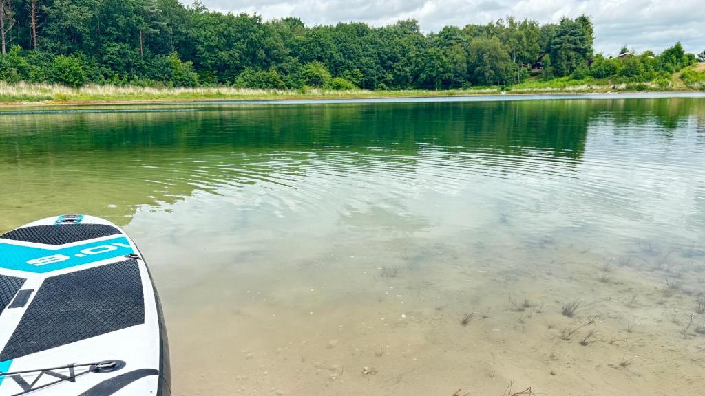 a paddle board sitting on the shore of a lake at Modernes Ferienhaus am See mit Garten in Wiefelstede