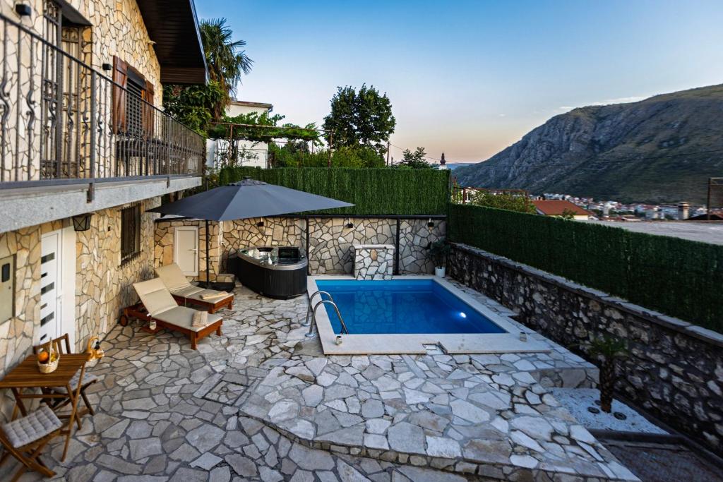 un patio trasero con piscina y sombrilla en Apartment Renela, en Mostar