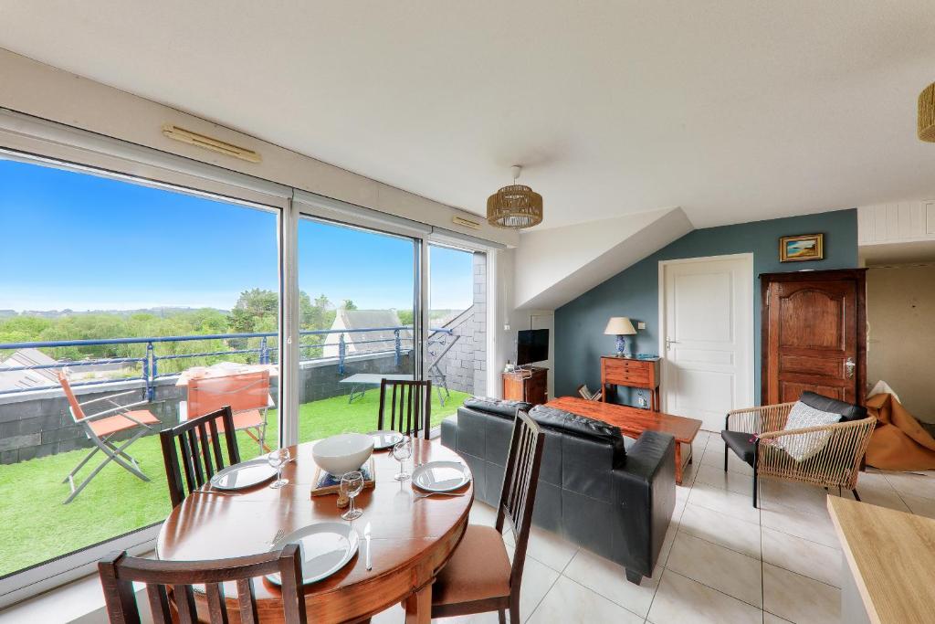 - un salon avec une table à manger et une grande fenêtre dans l'établissement Appartement pour 4 avec grand balcon, à Sarzeau