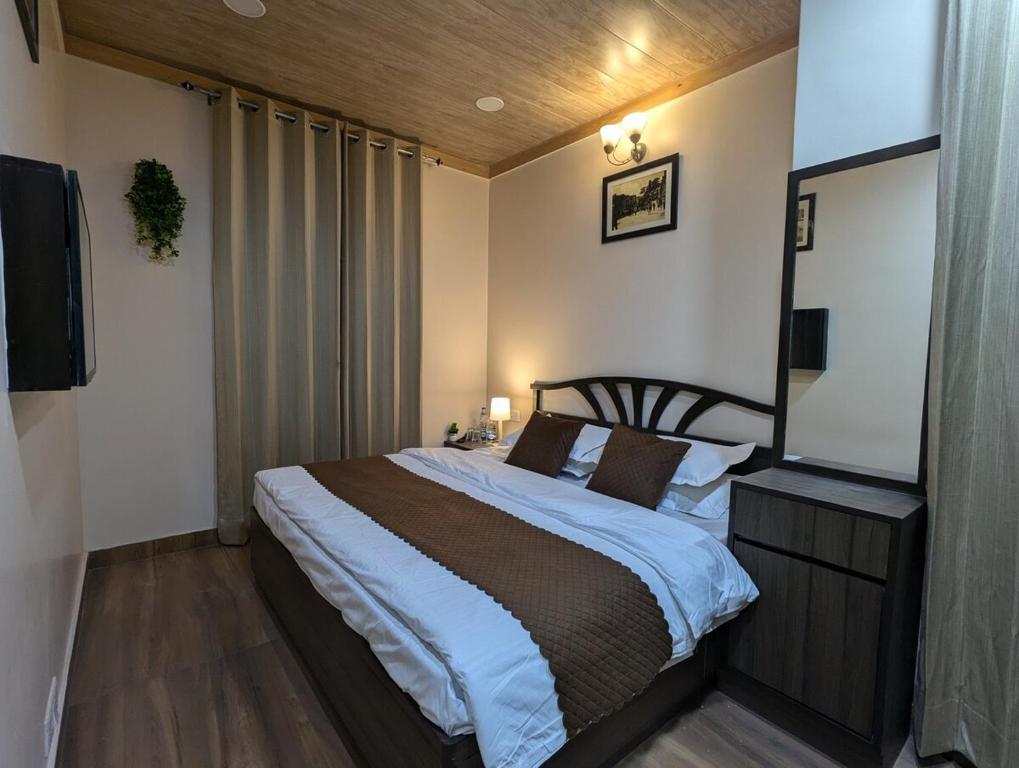 a bedroom with a large bed and a television at The Mall Ethos - On Mall Road - Kitchen - Sleeps 4 in Shimla