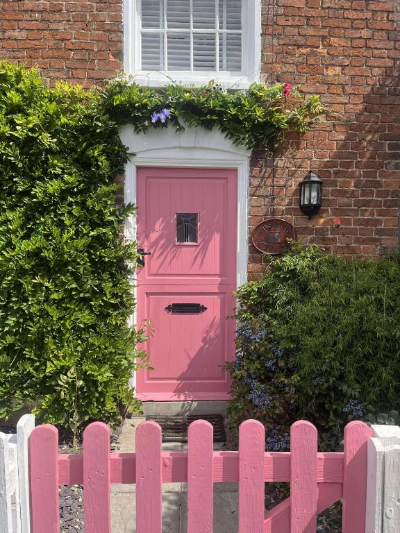 a pink door in a house with a pink fence at Jasmine Cottage in Burgh le Marsh