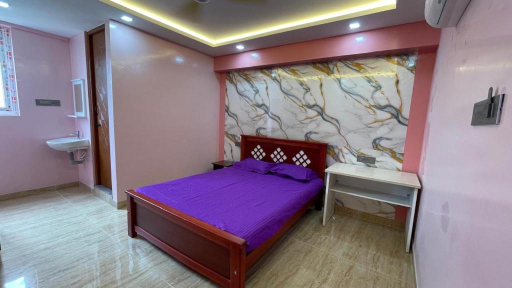 a small bedroom with a purple bed and a desk at Yellow Bliss Homestay in Coimbatore