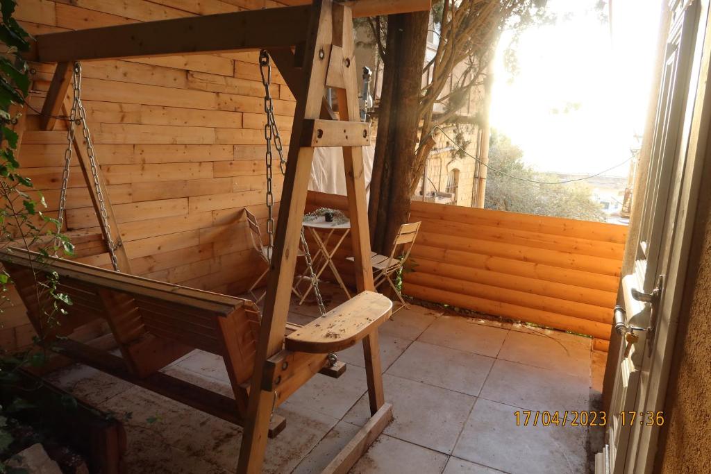 a wooden chair sitting on a porch next to a window at אחוזת ישוב הדעת in Safed