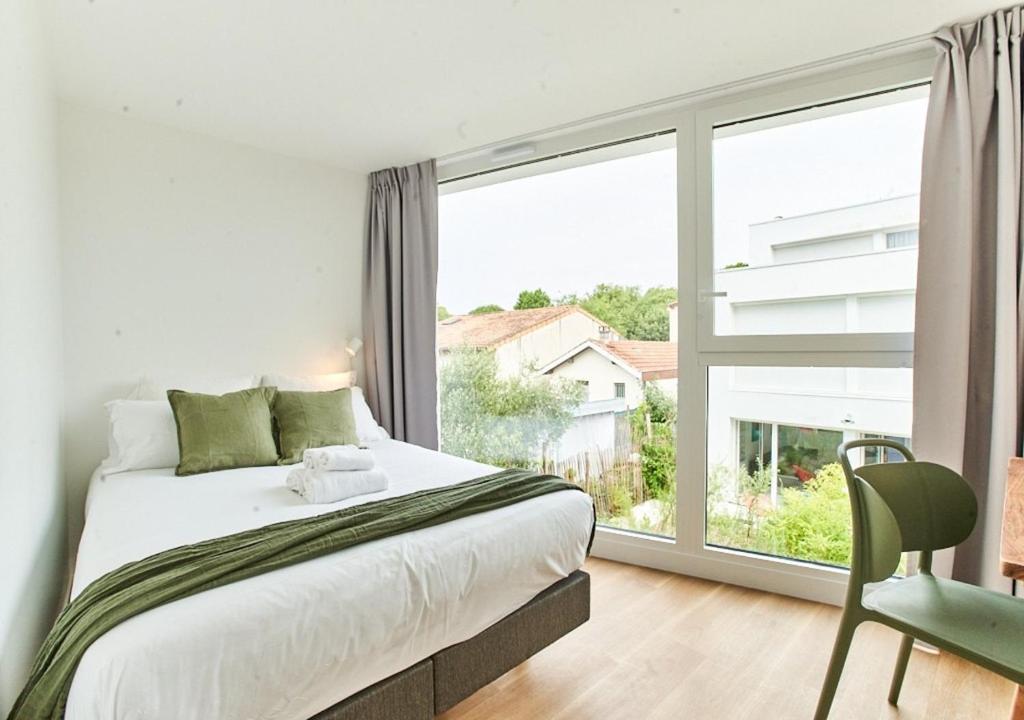 a bedroom with a bed and a large window at La Quinta Bordeaux-Bègles in Bègles