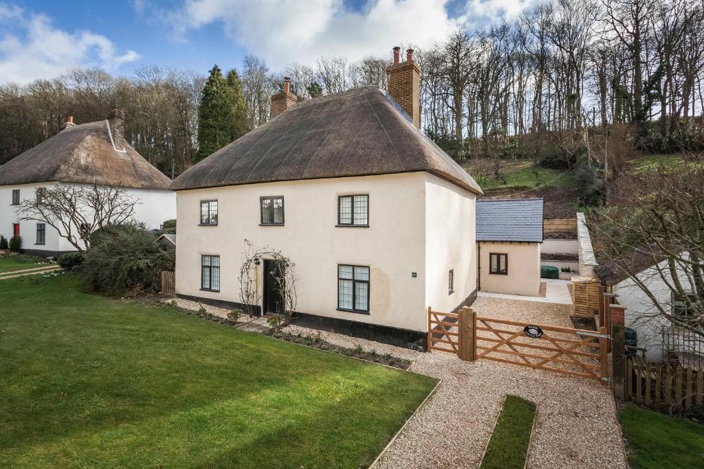 a large white house with a thatched roof at Three Little Pigs Luxury Cottage in Milton Abbas