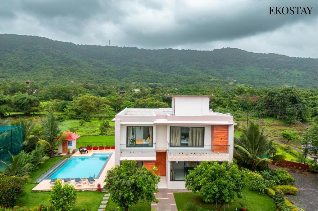 a house with a swimming pool in front of a mountain at EKOSTAY Luxe - Harmony Heights in Alibaug
