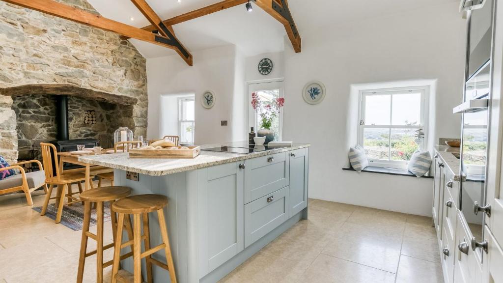 cocina con armarios blancos y chimenea de piedra en Fron Olau, en Nefyn