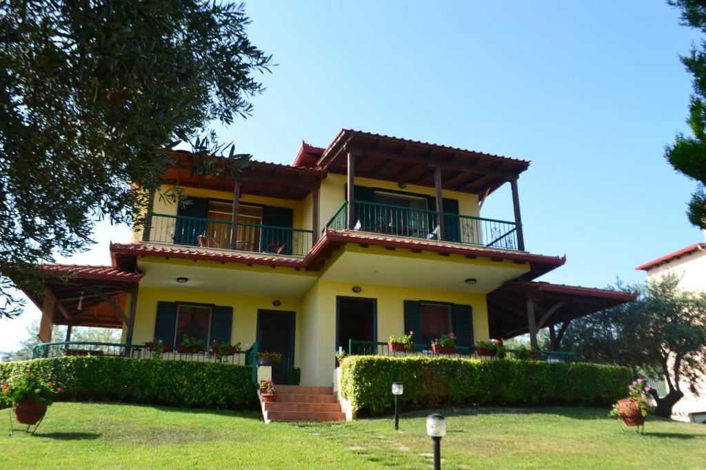 Una gran casa amarilla con balcones y arbustos en Apostolos, en Agios Nikolaos