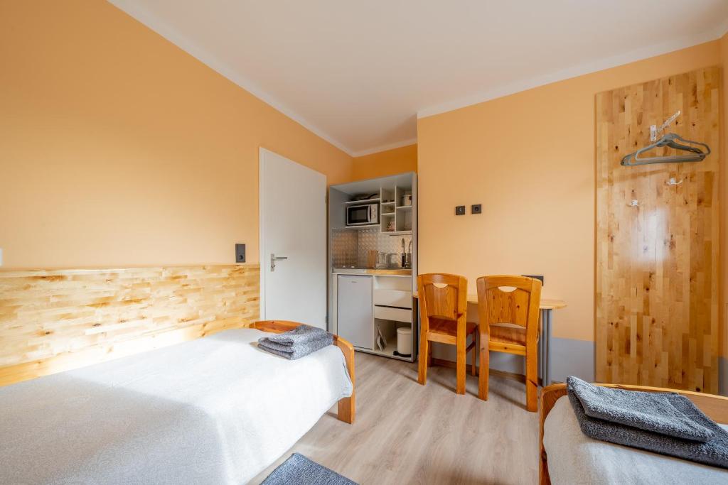 a bedroom with a bed and a table and chairs at Kompaktes Studiozimmer mit Pantryküche und Fußbodenheizung in der Nähe der Messe Dusche und WC werden gemeinschaftlich genutzt in Hannover
