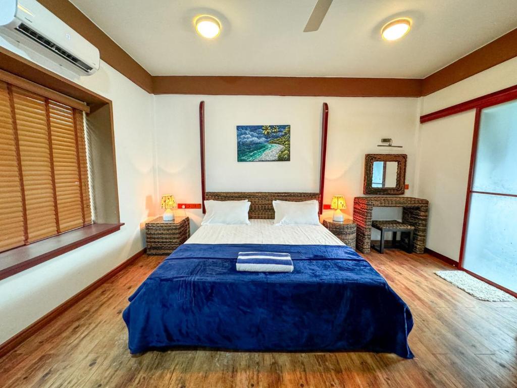 a bedroom with a large bed with a blue blanket at Long Beach Laamu Hotel in Gan