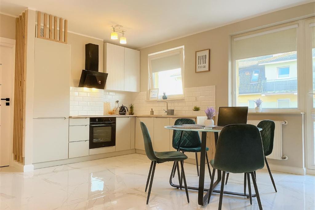 una cocina con sillas verdes y una mesa. en BALTIQ Apartments, en Ustka
