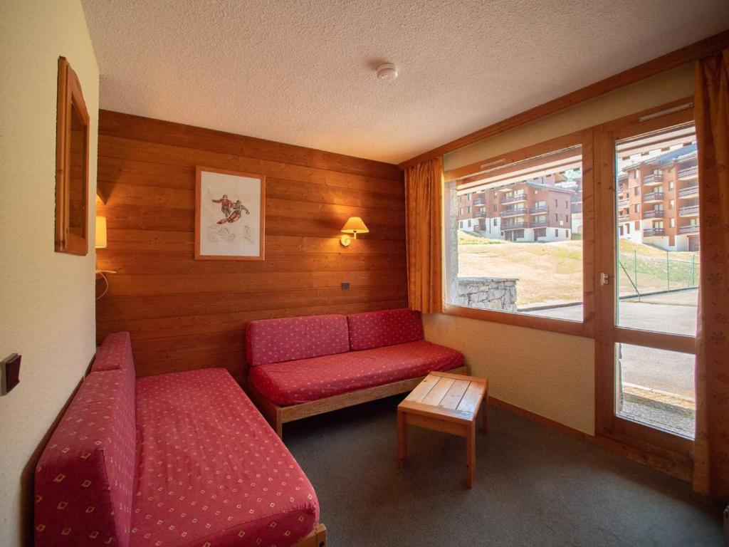 Cette petite chambre dispose d'un canapé rouge et d'une fenêtre. dans l'établissement Studio divisible avec terrasse, animaux acceptés - FR-1-291-783, à Valmorel