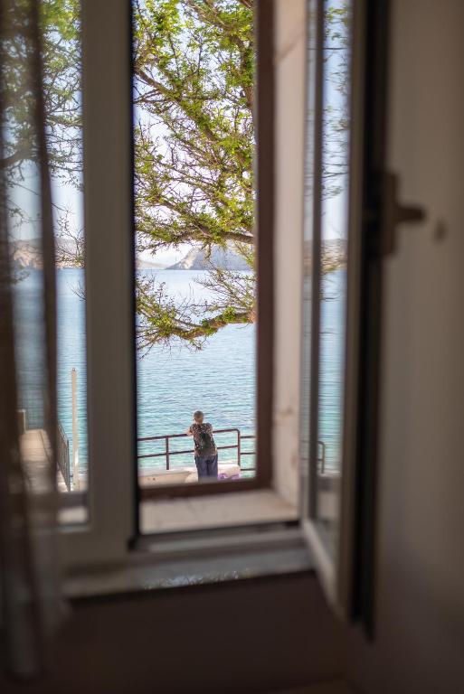 a person taking a picture of the water from a window at Apartments Mihael in Baška