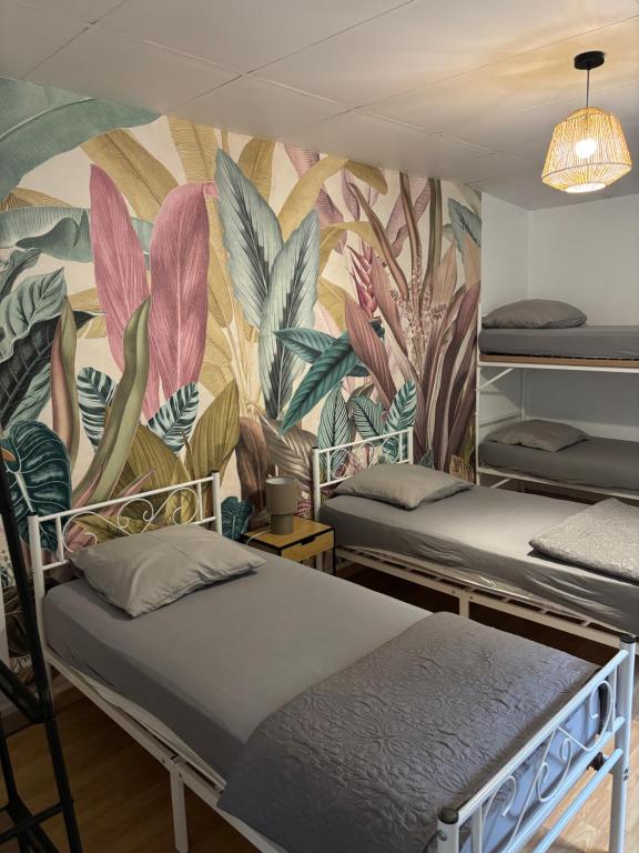 une chambre avec trois lits et une fresque de plantes dans l'établissement Les Chardonnays, à Baroville