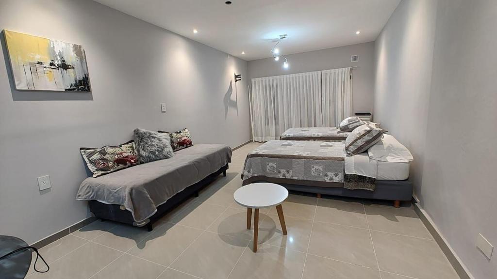 a bedroom with two beds and a table and a chair at Altos 679inn in Comodoro Rivadavia