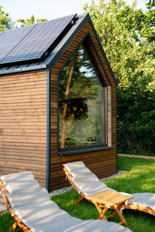 a cabin with two lounge chairs and a solar roof at Termalna Osada in Brenna