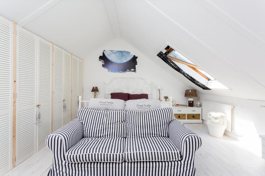 a living room with a striped chair and a bed at Silver Moon Bed & Breakfast in Voorschoten