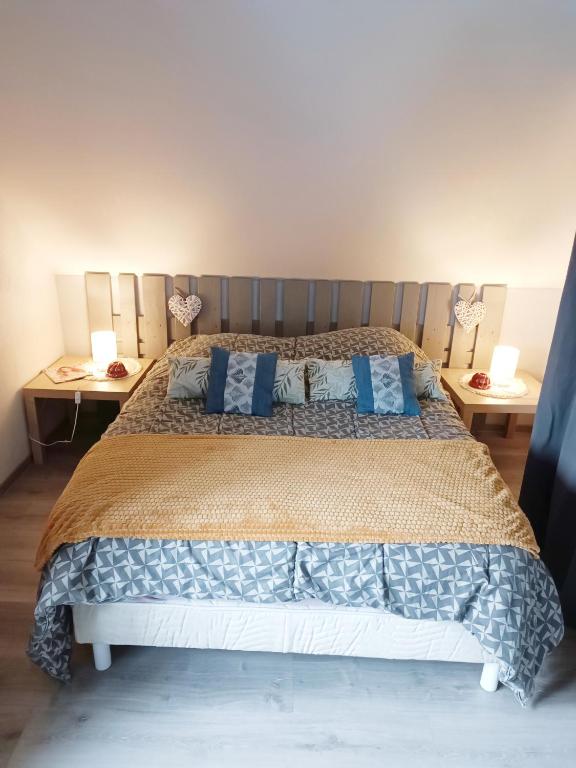 une chambre avec un grand lit avec des oreillers bleus dans l'établissement Au fil du Bonheur studio, à Surbourg