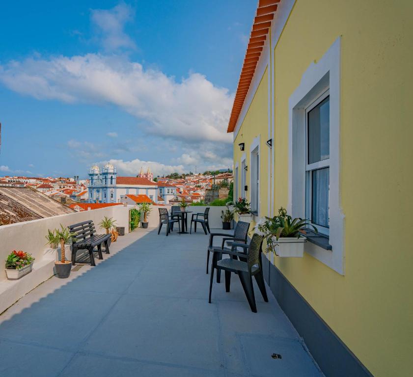 ein Balkon mit Stühlen und Blick auf die Stadt in der Unterkunft Yellow House - Casa 1 in Angra do Heroísmo